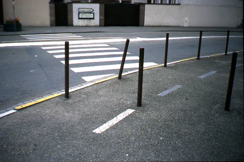 Eine Reihe schräger Metallpoller an einem Fußgängerüberweg – Pollerforschung und urbane Verkehrsregulierung im Fokus.