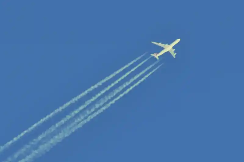 Kondensstreifen hinter einem Flugzeug vor klarem blauen Himmel.